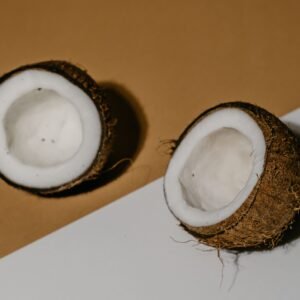 Halved coconuts on a brown and white background, showcasing the texture and freshness of the fruit.